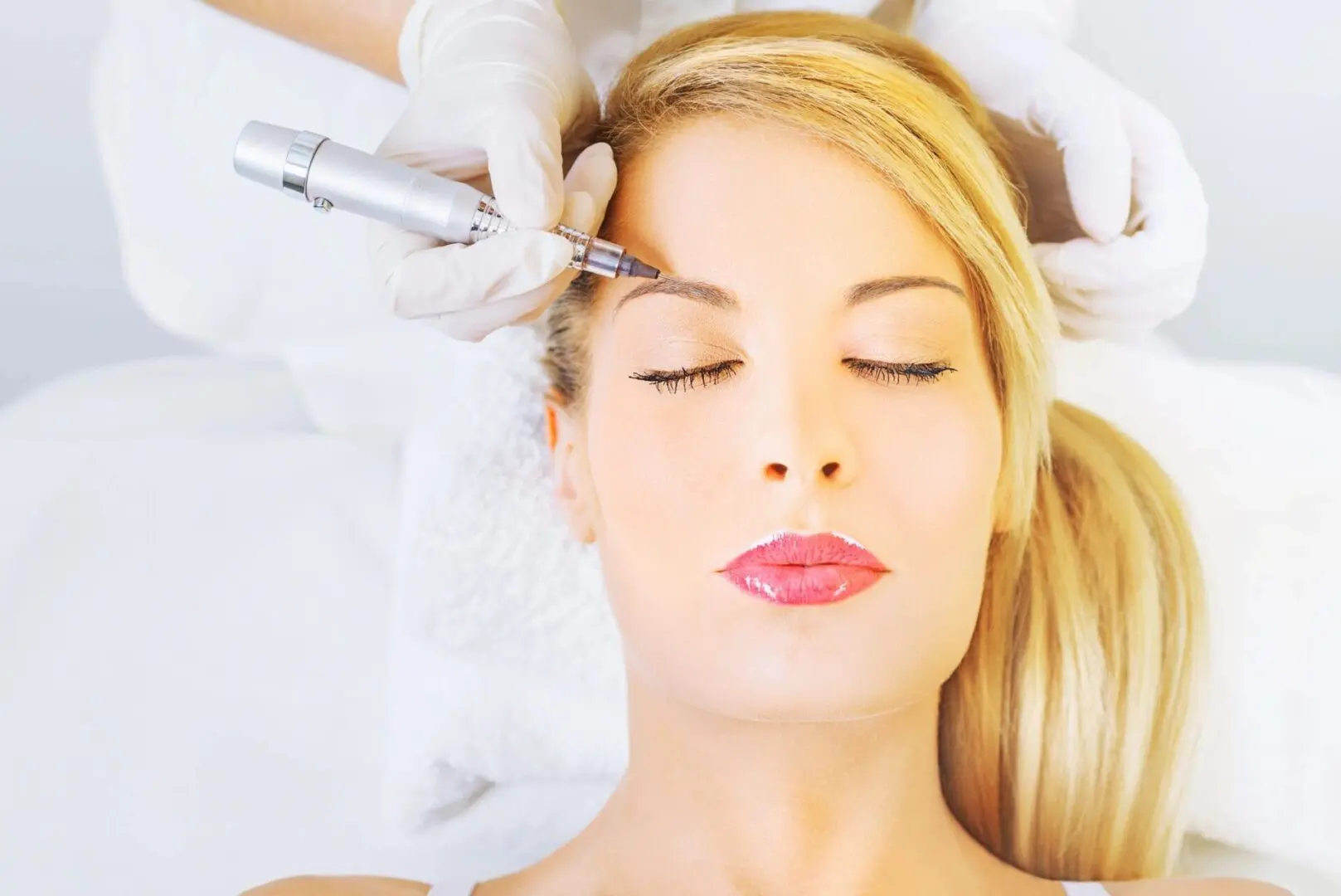 A woman getting her eyebrows threaded by an esthetician.